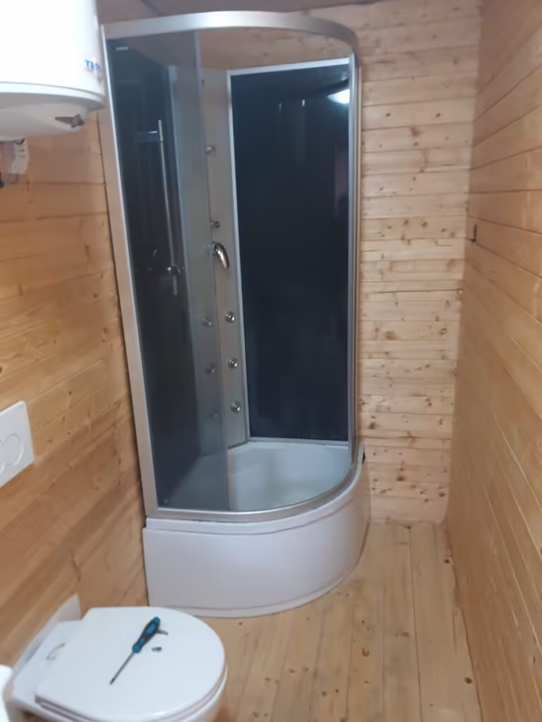 Starý sprchový kout s vysokou vaničkou.