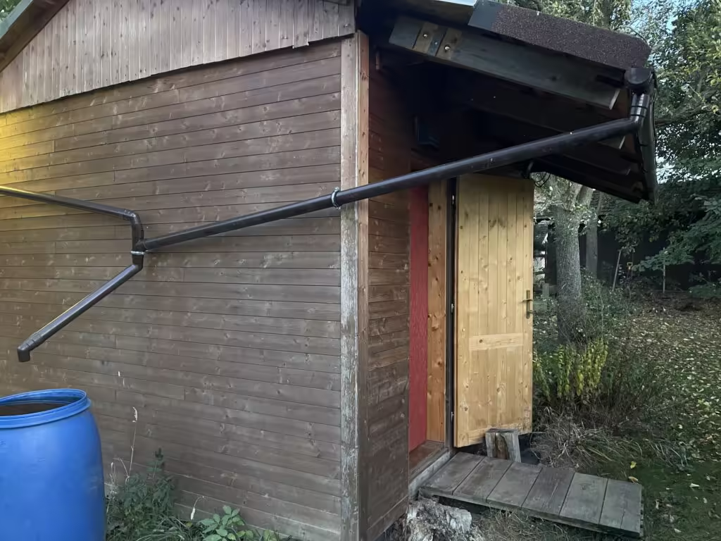 Západní svatyně pro pobyt ve tmě se vstupními dveřmi a sudem na dešťovou vodu